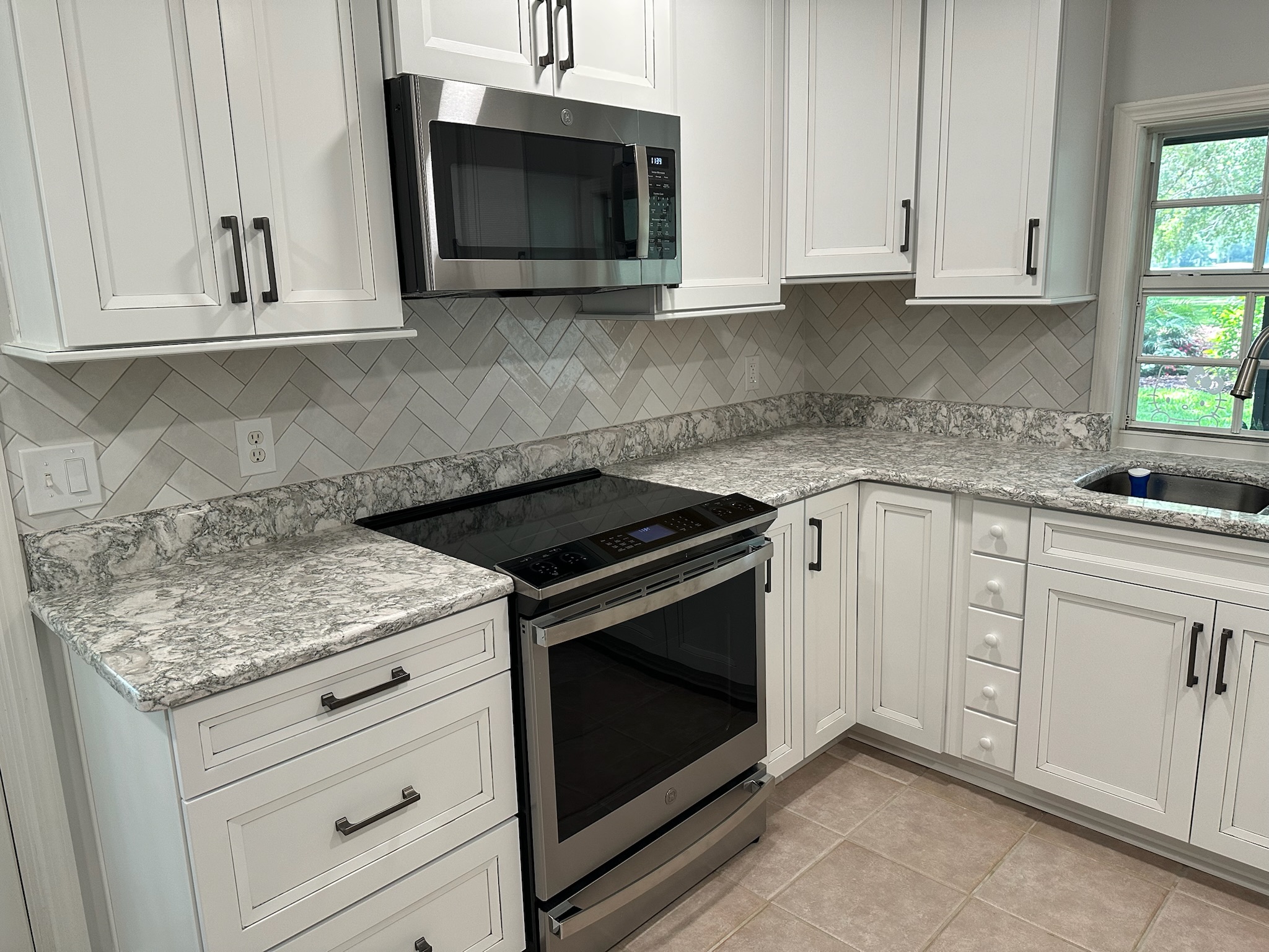 Gray Herringbone Backsplash with White Cabinets.