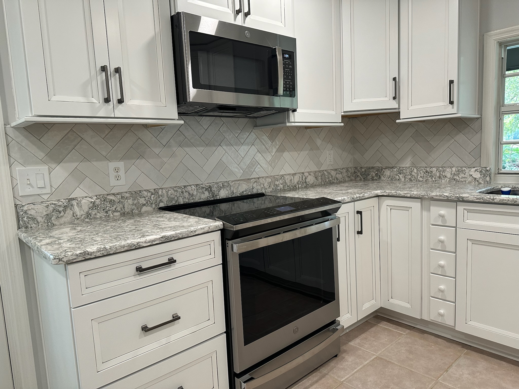Gray Herringbone Backsplash with White Cabinets.