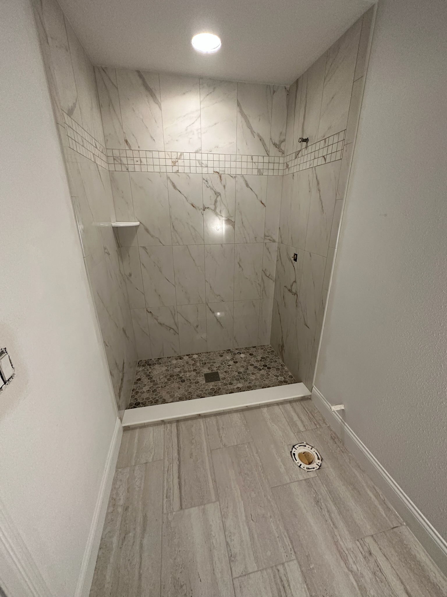Marble Shower with a Mosaic Accent Stripe.