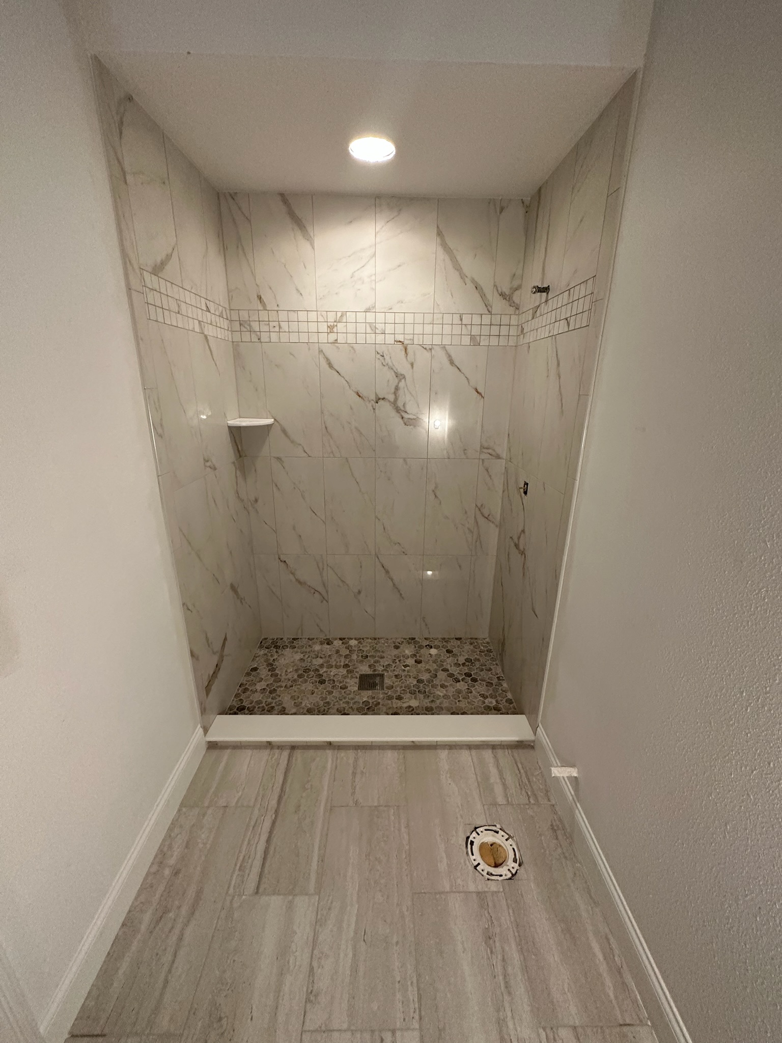 Marble Shower with a Mosaic Accent Stripe.