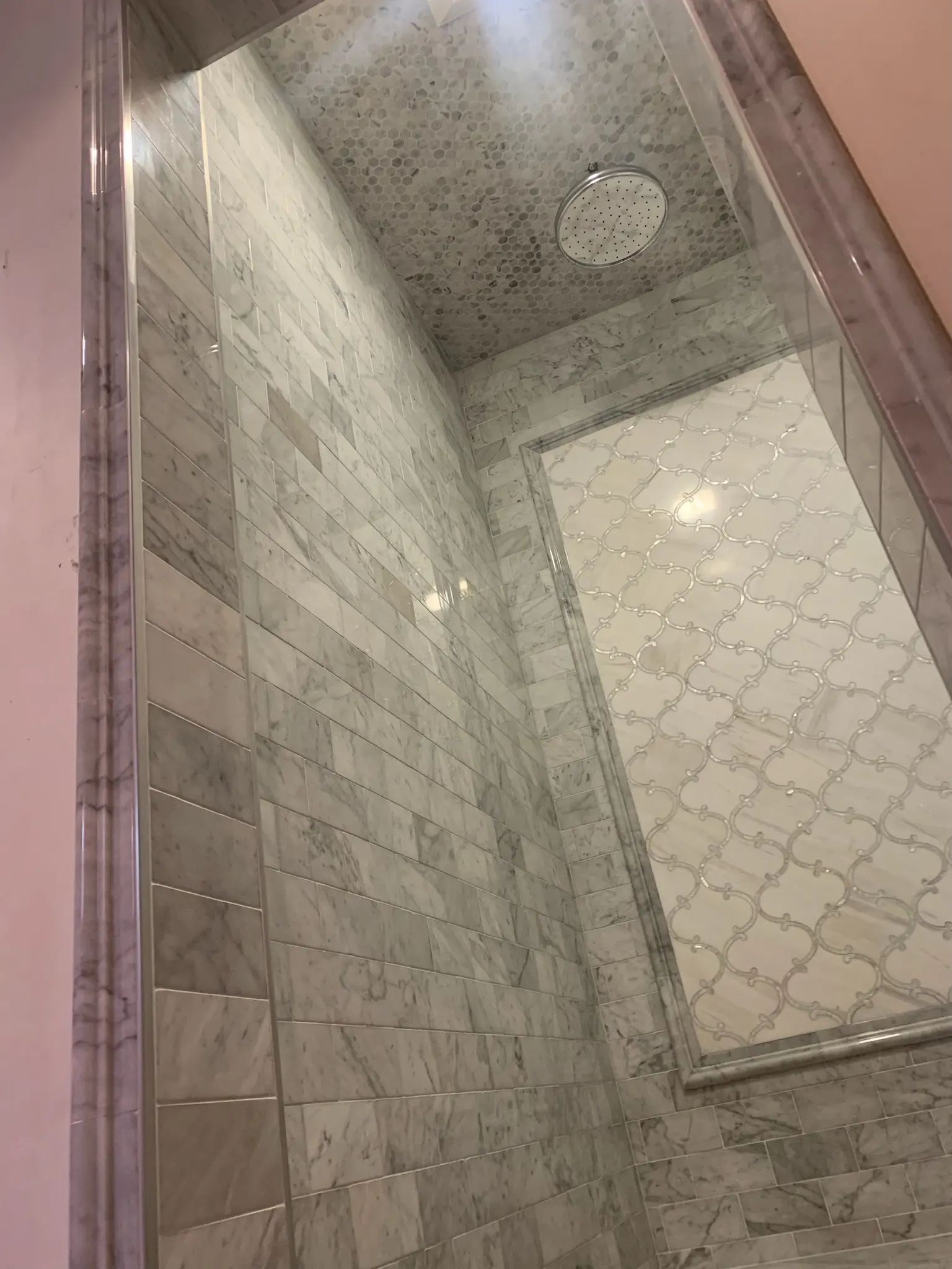 Gray marble tiled shower walls surrounding a framed decorative accent panel.