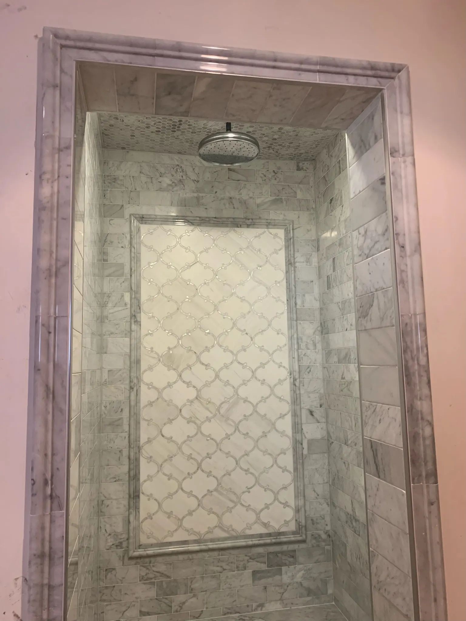 Doorway view of a gray marble shower with a framed back-wall feature.