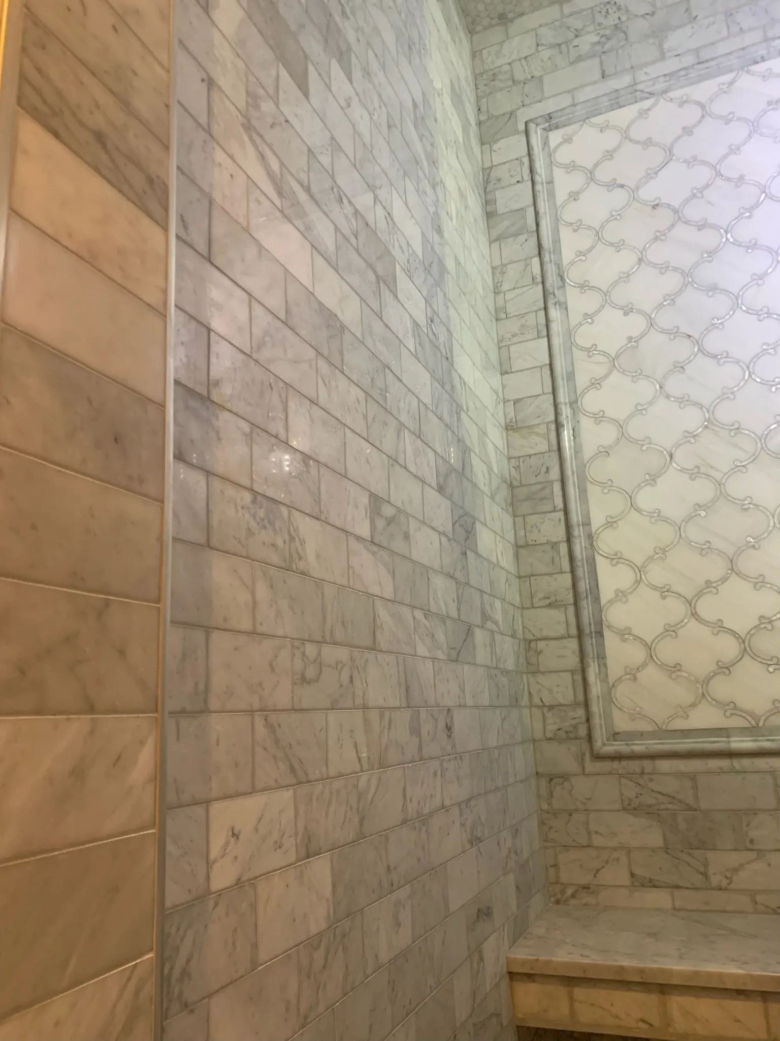 Gray subway marble shower wall meeting a built-in tiled bench.