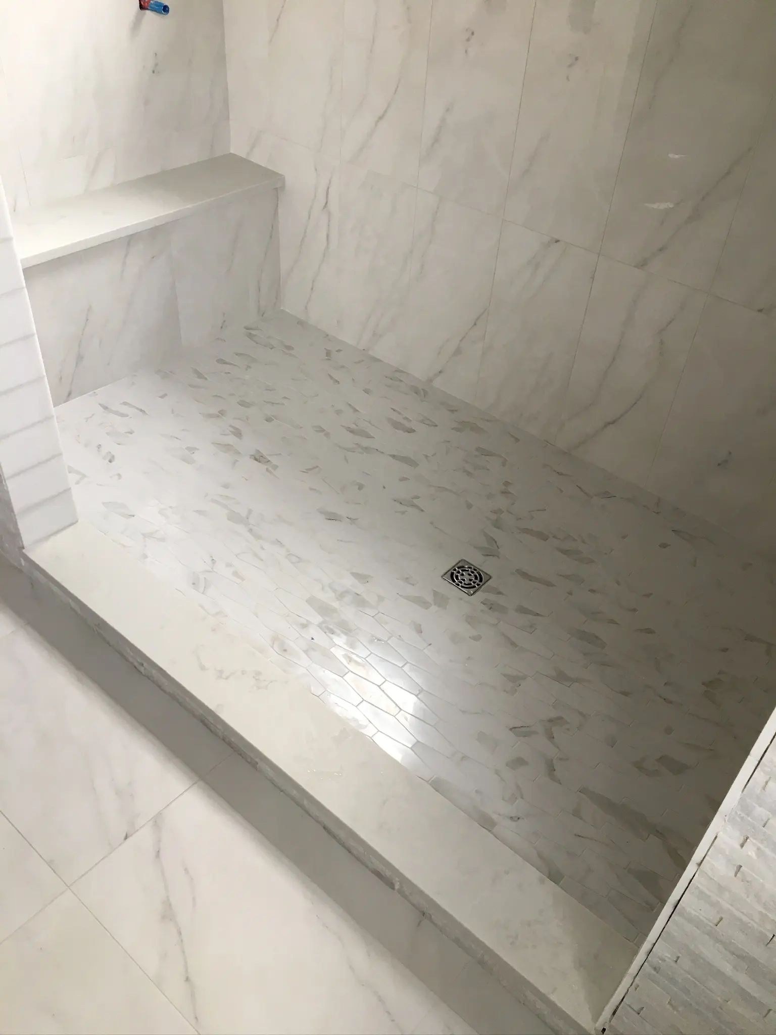 Close view of a tiled shower bench and small-format mosaic shower floor.