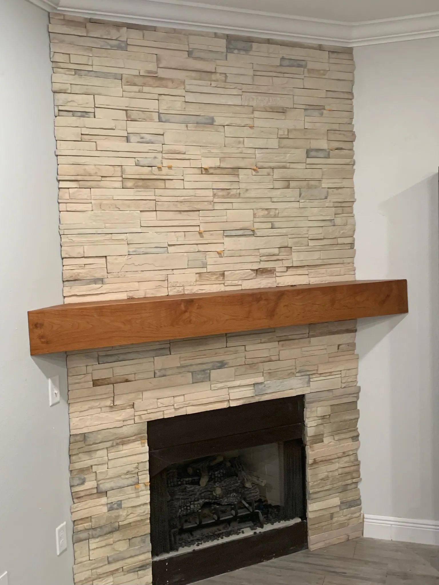 Full-height cream ledgestone fireplace surround with a substantial natural wood mantel.