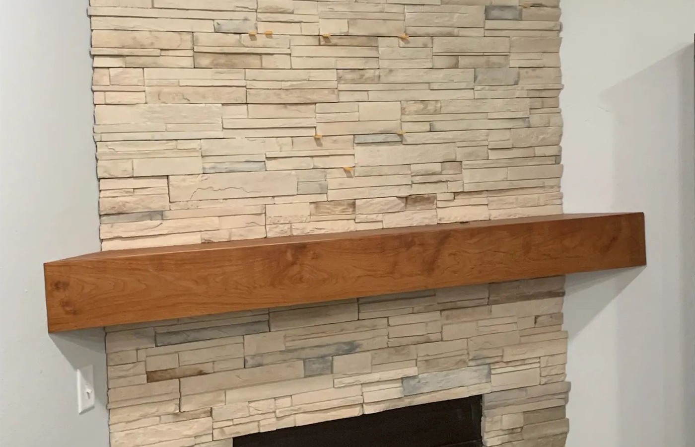 Cream ledgestone fireplace surround with a thick natural wood mantel.