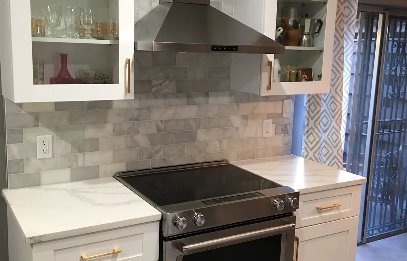 Bright white kitchen with a soft gray marble-look tile backsplash behind the range.