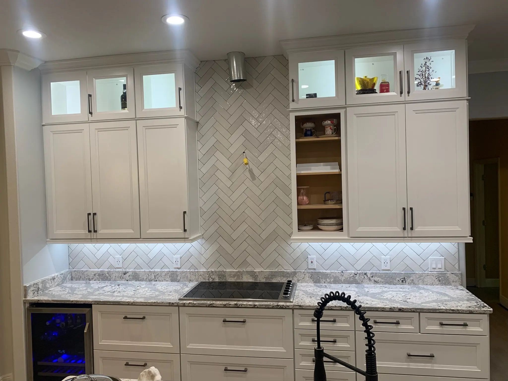 White cabinetry surrounding a full-height herringbone range backsplash and matching lower band.