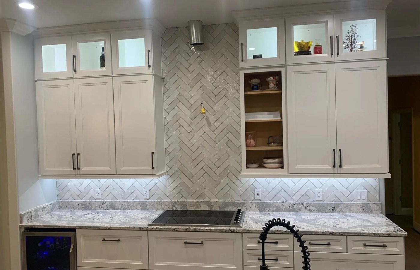 White kitchen with a marble-look herringbone backsplash and full-height range accent.