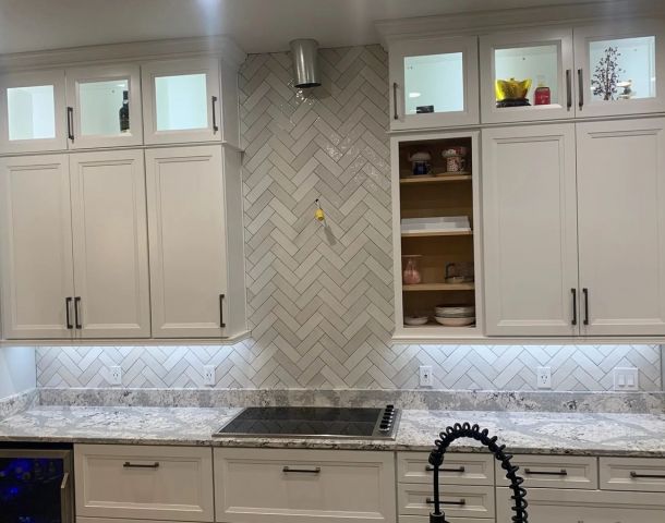 White kitchen with a marble-look herringbone backsplash and full-height range accent.