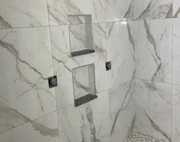 Large-format marble-look shower with recessed niches and a basketweave mosaic floor.