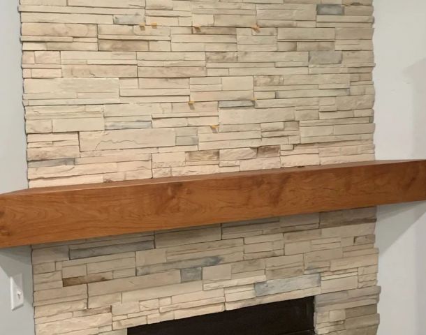 Cream ledgestone fireplace surround with a thick natural wood mantel.