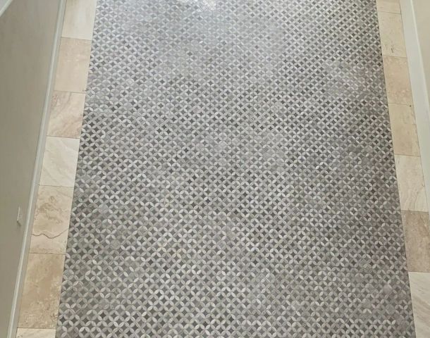 Geometric mosaic tile hallway floor framed by a wide marble-look border.