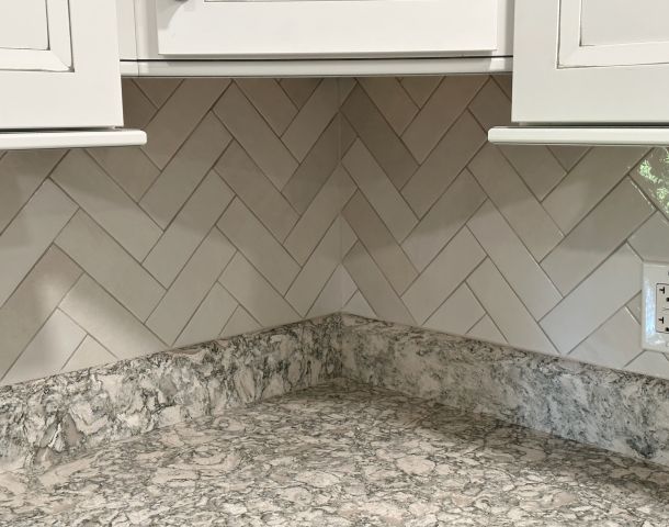 Gray Herringbone Backsplash with White Cabinets.